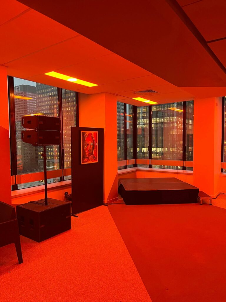 Espace événementiel avec sonorisation, éclairage rouge et scène, vue panoramique sur la ville.